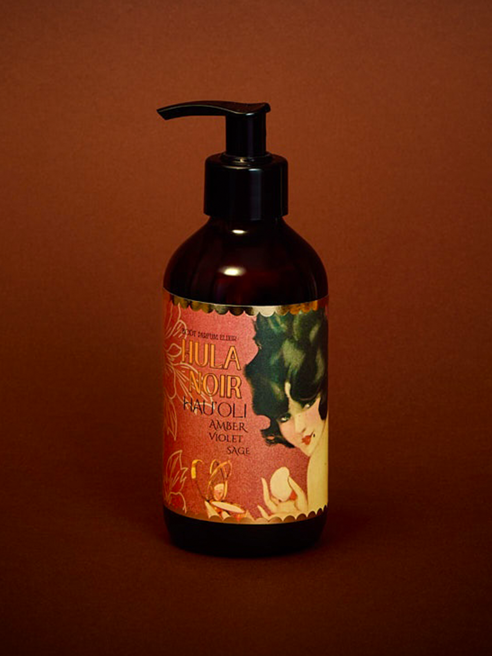 An amber glass pump bottle of Hula Noir Body Oil with a black pump, set against a solid dark reddish-brown background. 